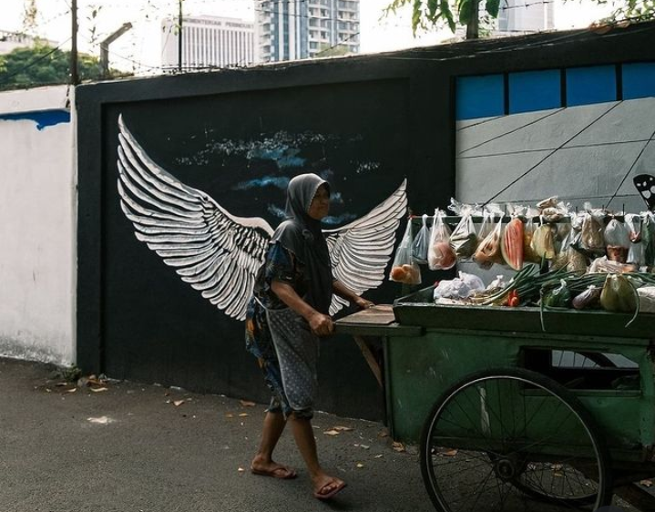 Viral Potret Ibu Penjual Sayur di Depan Mural Sepasang Sayap, Netizen: Real Simbol Kekuatan Seorang Ibu